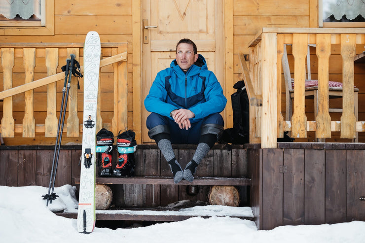 Sciatore con gli sci di fronte ad una baita nelle Dolomiti